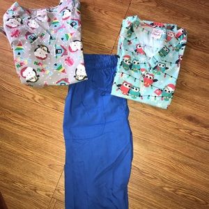 Two Christmas scrub tops with blue scrub pants.
